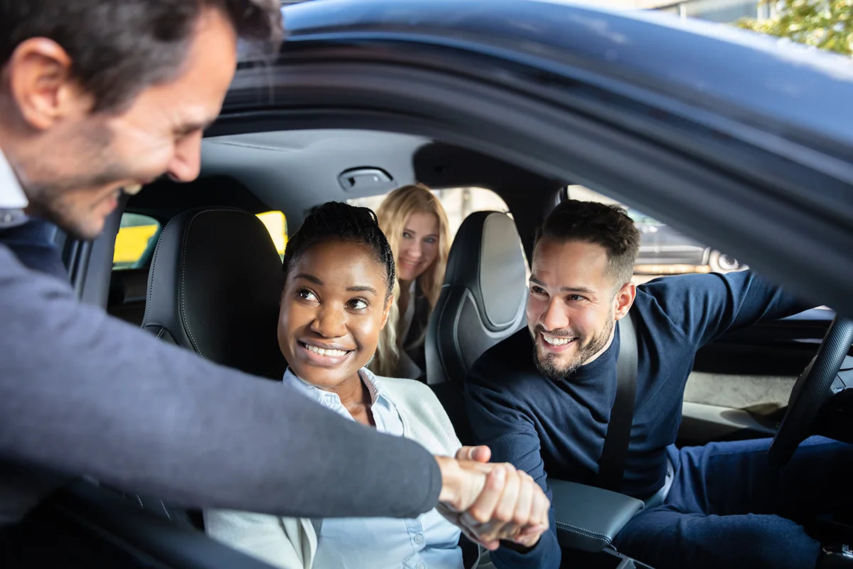 People picking up another person car sharing shaking hands through window